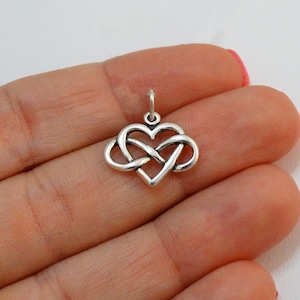 May include: Silver infinity heart charm pendant. The charm is in the shape of a heart with an infinity knot design.