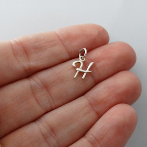 May include: A silver charm in the shape of the letter H. The charm is small and delicate, and it would be perfect for adding a personal touch to a necklace or bracelet.
