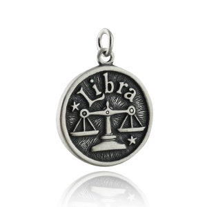 May include: Silver charm with a black and white image of the Libra zodiac symbol and the word "Libra" in a stylized font.