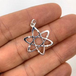May include: A silver atom pendant with clear cubic zirconia stones. The pendant is in the shape of an atom with a central nucleus and orbiting electrons.