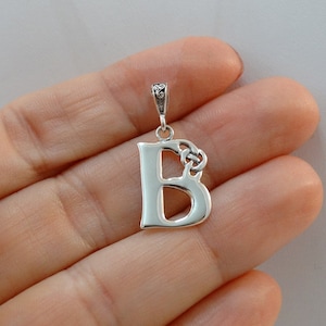 May include: Silver pendant featuring the letter B with a Celtic knot design. The pendant is on a white background.