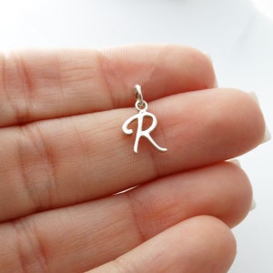 May include: Silver charm with a cursive letter R pendant.