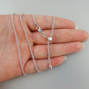 May include: A silver chain necklace with a sliding clasp and a beaded design. The necklace is adjustable in length.