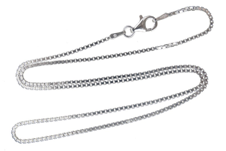 May include: A silver chain necklace with a lobster clasp fastening. The chain is made of small, linked squares.