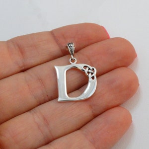 May include: Silver pendant featuring the letter D with a Celtic knot design.