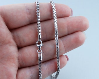 May include: A silver chain necklace with a lobster clasp. The chain is a box style and is approximately 20 inches long.