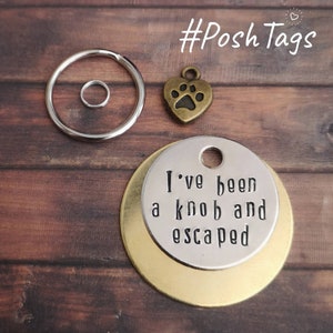 May include: A silver key ring with a round charm that says "I've been a knob and escaped". The charm is layered on top of a gold round charm. A small bronze heart charm with a paw print is also included.
