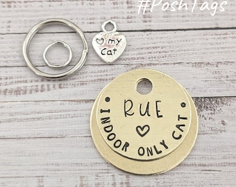 May include: Gold round cat ID tag with the text "Rue Indoor Only Cat" and a small heart symbol. The tag is attached to a silver key ring with a small heart charm that says "My Cat".