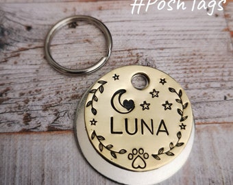 Könnte beinhalten: Ein goldfarbener Hundemarkenanhänger mit silberner Rückseite. Der Anhänger zeigt einen zunehmenden Mond mit einem Herzen, Sternen und einem Pfotenabdruck. Der Name "LUNA" ist in den Anhänger graviert.
