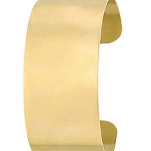 May include: A simple gold cuff bracelet. The bracelet is made of a smooth, polished metal and has a rounded shape.