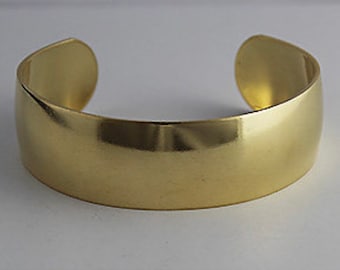 May include: A simple, polished gold bangle bracelet. The bracelet is smooth and has a rounded shape.