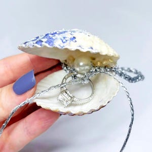 Caja para anillos con forma de concha marina: Soporte artesanal para anillos de compromiso con temática costera.