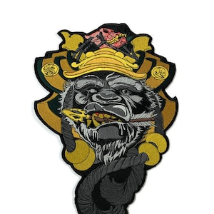 Könnte beinhalten: Gestickter Aufnäher mit einem Gorilla, der einen Samurai-Helm mit gold-schwarzem Design trägt. Der Gorilla hält eine Lanze und hat einen grimmigen Gesichtsausdruck.