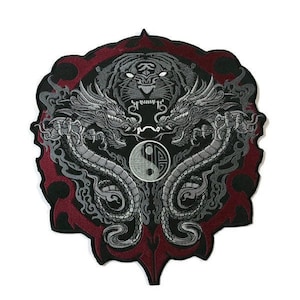 May include: A black and silver embroidered patch featuring a tiger, two dragons, and a yin yang symbol. The patch has a red border and is surrounded by a black and silver design.