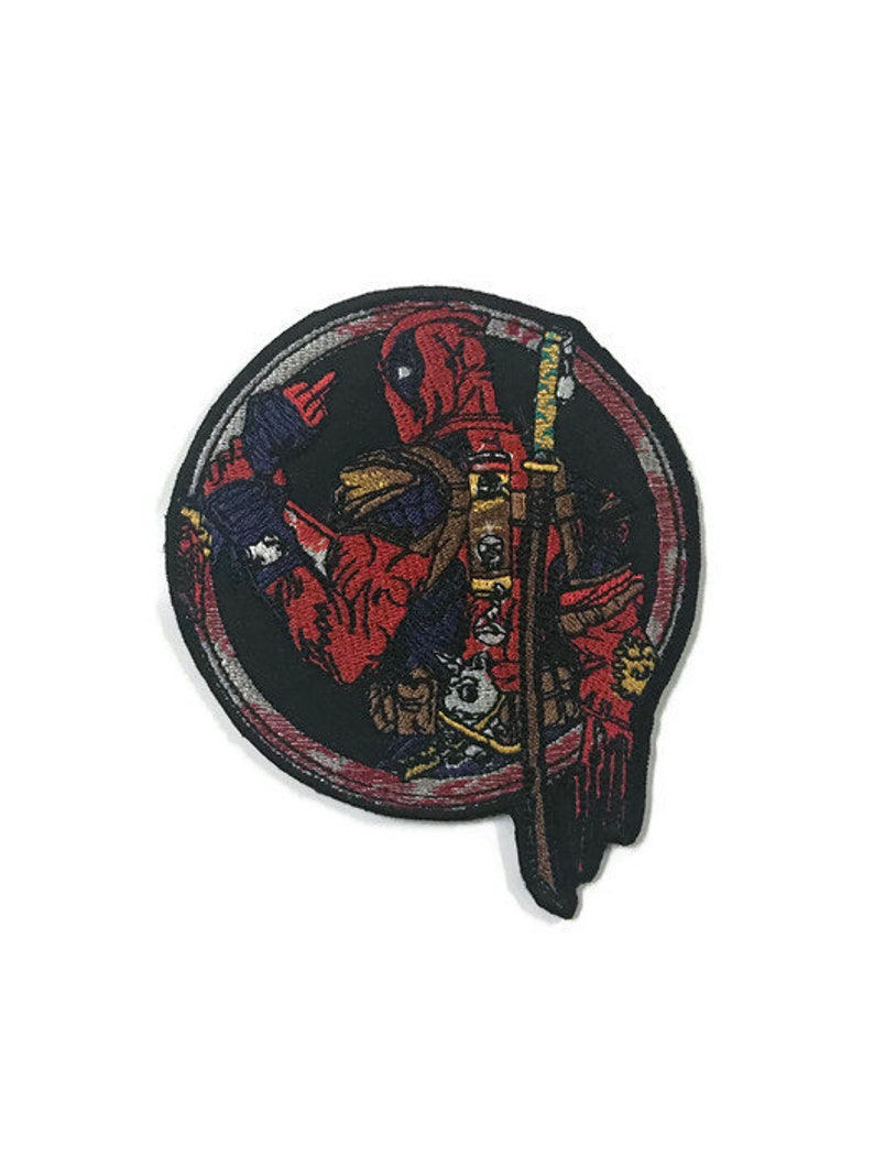 May include: Circular embroidered patch of Deadpool in red, black, and grey. The patch shows the character with a sword, set against a black background. Suitable for application on clothing or accessories, such as jackets or bags.
