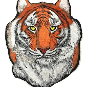 May include: Embroidered iron-on patch of a tiger's face. The tiger has orange and black stripes, white fur around its mouth, and yellow eyes.