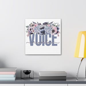 以下が含まれることがあります： 紫、ピンク、青の花のウォーターカラーのフラワーデザイン。"VOICE"という単語が大きな青い文字で書かれており、その下に"reporter"という単語が筆記体で書かれています。