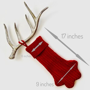 Op de afbeelding: Rode gebreide kerstsok met een witte boord, 43 cm lang en 23 cm breed. De sok heeft een lus aan de bovenkant om op te hangen en is 15 cm breed aan de boord.