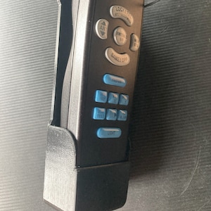 May include: A black remote control with blue buttons. The buttons are labeled "Lock/Rel", "Xmit/Ind", "Same/Opp", "Pasten", "St 100", "St Test", "10", "Blank", and "Light".