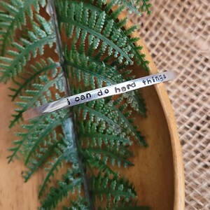 May include: Silver bracelet with the inscription "I can do hard things".