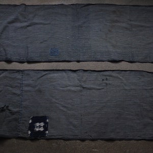 以下が含まれることがあります： ざらざらした質感の濃い青色の布が2枚。布は小さな布の切れ端でパッチワークされている。布は藍染めされている可能性が高いです。