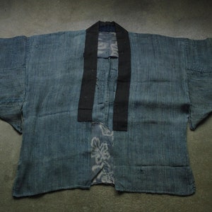 Puede incluir: Un kimono de algodón a rayas azul y negro con cuello negro y un patrón floral en la parte delantera.