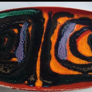 May include: Rectangular ceramic dish with a vibrant abstract design. The dish features a red border, with a central pattern of black, orange, purple, and green swirls. The design is reminiscent of mid-century modern art.
