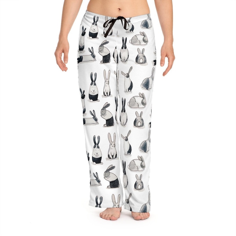 Puede incluir: Pantal&oacute;n de pijama blanco con un patr&oacute;n de conejo blanco y negro. Los conejos est&aacute;n en varias poses, incluyendo de pie, sentados y acostados.