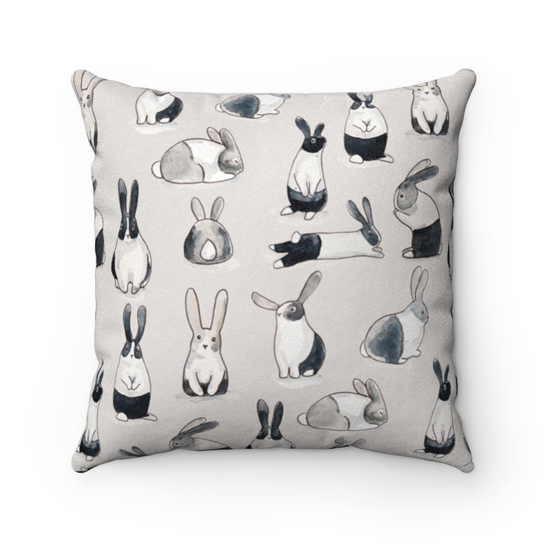 May include: A gray and white throw pillow with a repeating pattern of black and white rabbits in various poses. The rabbits are drawn in a watercolor style.