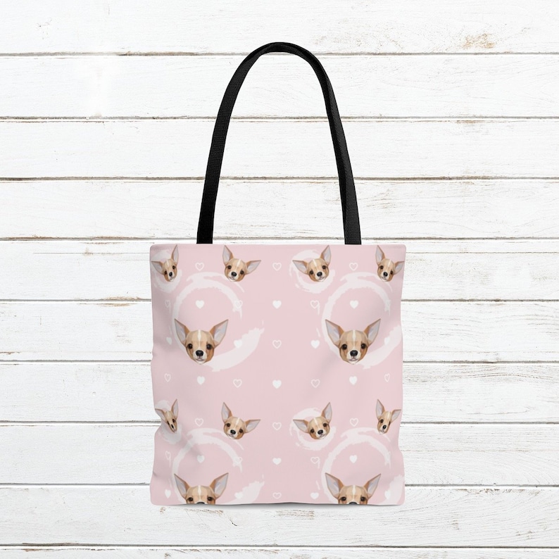 May include: A pink tote bag with a repeating pattern of white hearts and brown chihuahua faces. The bag has black handles.