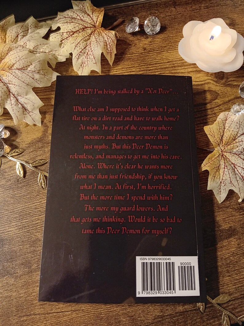 May include: A black book cover with white text that reads "HELP! I'm being stalked by a "Not Deer"."  What else am I supposed to think when I get a flat tire on a dirt road and have to walk home? At night. In a part of the country where monsters and demons are more than just myths. But this Deer Demon is relentless, and manages to get me into his cave. Alone. Where it's clear he wants more from me than just friendship, if you know what I mean. At first, I'm horrified. But the more time I spend with him? The more my guard lowers. And that gets me thinking. Would it be so bad to tame this Deer Demon for myself?"  The book cover also includes an ISBN number and barcode.