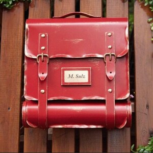 uma caixa de correio em forma de mochila escolar com um cartão de visita