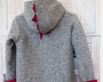 Puede incluir: Chaqueta gris con capucha y detalles en fieltro rojo en la espalda y las mangas.
