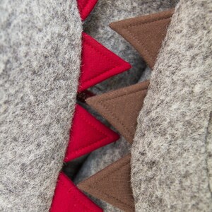 May include: A gray hooded sweatshirt with red and brown triangular patches sewn on the back. The patches are arranged in a row, with the red patches on the left and the brown patches on the right.