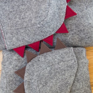 May include: Gray felt hooded garment with red and brown felt spikes. The hood is folded down and the spikes are visible.