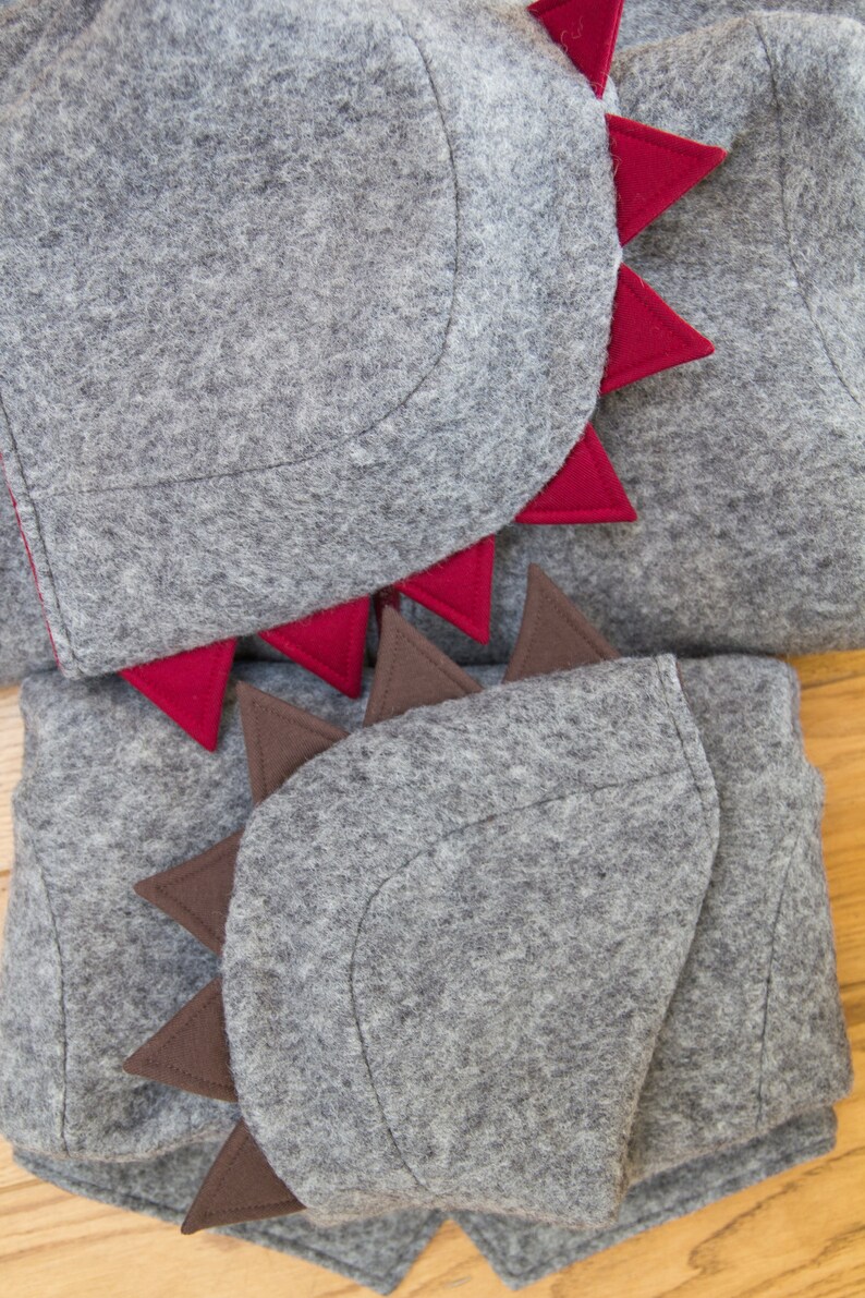 May include: Gray felt hooded garment with red and brown felt spikes. The hood is folded down and the spikes are visible.