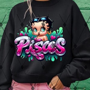 May include: Black sweatshirt featuring a pink and green graphic of a cartoon character with the word "Pisces" in pink and green lettering.