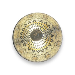 May include: A round, gold mosaic ceiling light fixture with a floral design. The light fixture has a central dome with a smaller, circular light source.