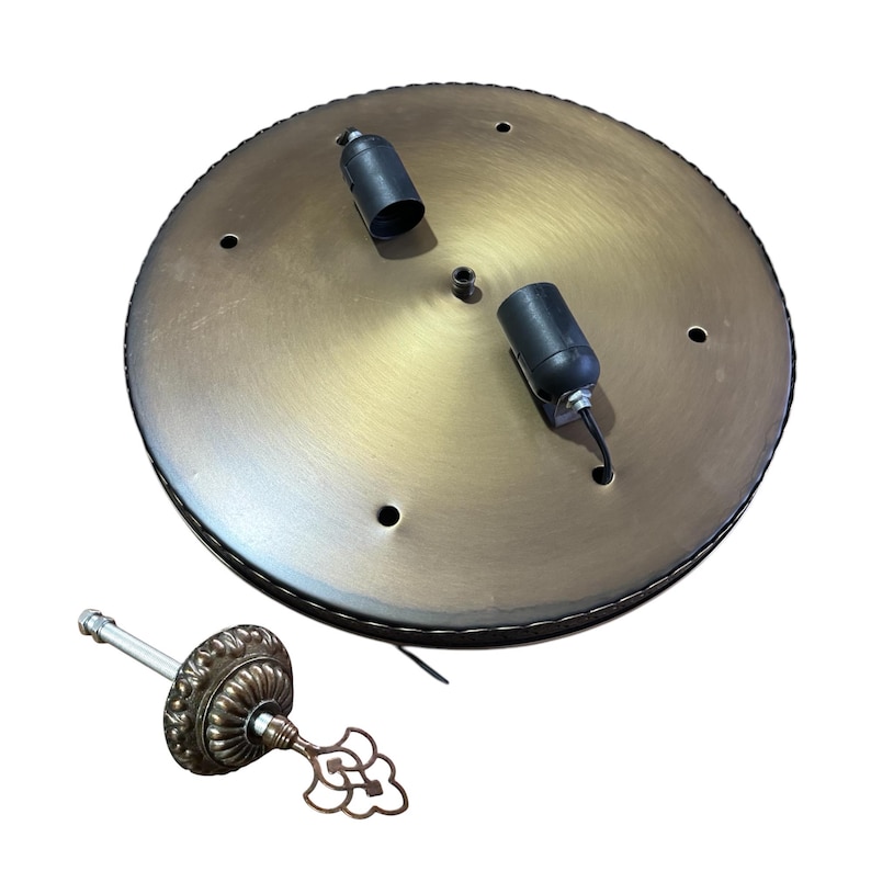 May include: A brass ceiling plate with two black electrical sockets and a decorative metal finial.