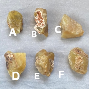 May include: Six pieces of yellow-brown, translucent, rough-cut, natural stone. The stones are labeled A, B, C, D, E, and F.