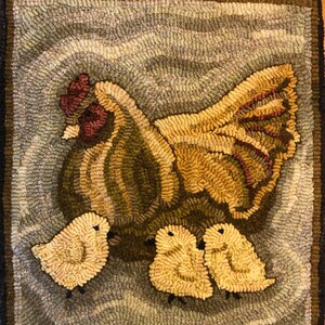 Puede incluir: Una alfombra hecha a mano que representa una gallina marr&oacute;n y amarilla con tres pollitos amarillos. La gallina est&aacute; de pie sobre un fondo azul claro con un patr&oacute;n ondulado.