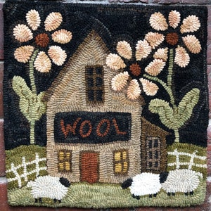 May include: Hand-hooked wool rug featuring a house with the word "WOOL" above the door, flanked by large flowers. Two sheep graze in the foreground. The rug has a black background with a brick-like border, and is a charming piece of home decor.
