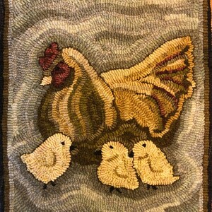 Puede incluir: Una gallina marr&oacute;n y amarilla con cresta y barbillas rojas se sienta en una alfombra azul y blanca con tres pollitos amarillos.