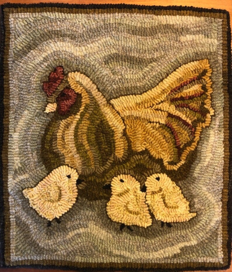 Puede incluir: Una gallina marr&oacute;n y amarilla con cresta y barbillas rojas se sienta en una alfombra azul y blanca con tres pollitos amarillos.