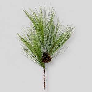 May include: A decorative artificial pine branch featuring long, slender green needles and a single brown pinecone attached to a central stem. The branch displays a realistic texture with varying shades of green throughout the needle clusters.