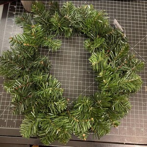 May include: A green artificial evergreen wreath, perfect for decorating for the holidays.