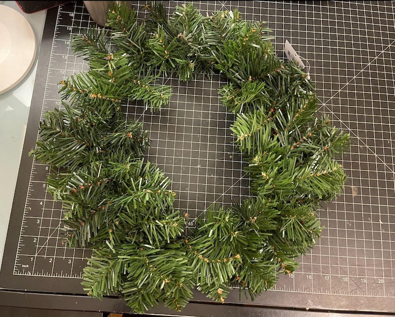 May include: A green artificial evergreen wreath, perfect for decorating for the holidays.