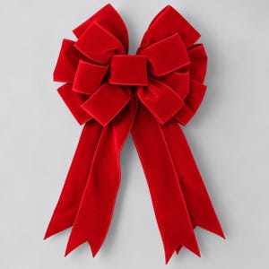 May include: A large, vibrant red velvet bow featuring multiple layered loops and two long, flowing tails with V-shaped notched ends. The fabric has a soft, matte texture, and the bow is constructed with a central knot securing the loops.