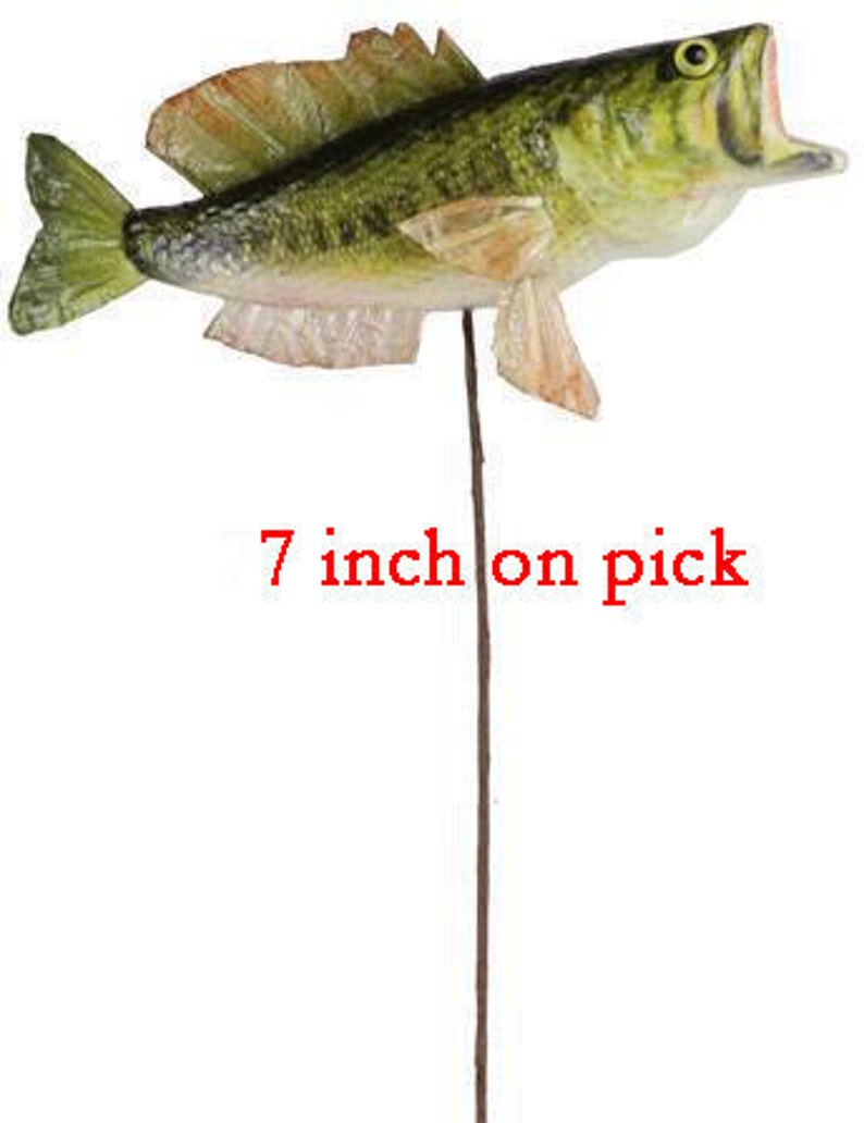 May include: A decorative fish on a pick, approximately 7 inches (17.78 cm) long. The fish has green, yellow, and orange coloring with an open mouth. The text "7 inch on pick" is printed in red.