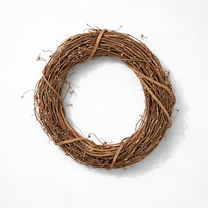 May include: A circular wreath made of intertwined brown twigs and branches. The wreath is tied together with a lighter brown band, creating a natural and rustic aesthetic. Perfect for seasonal home decor.